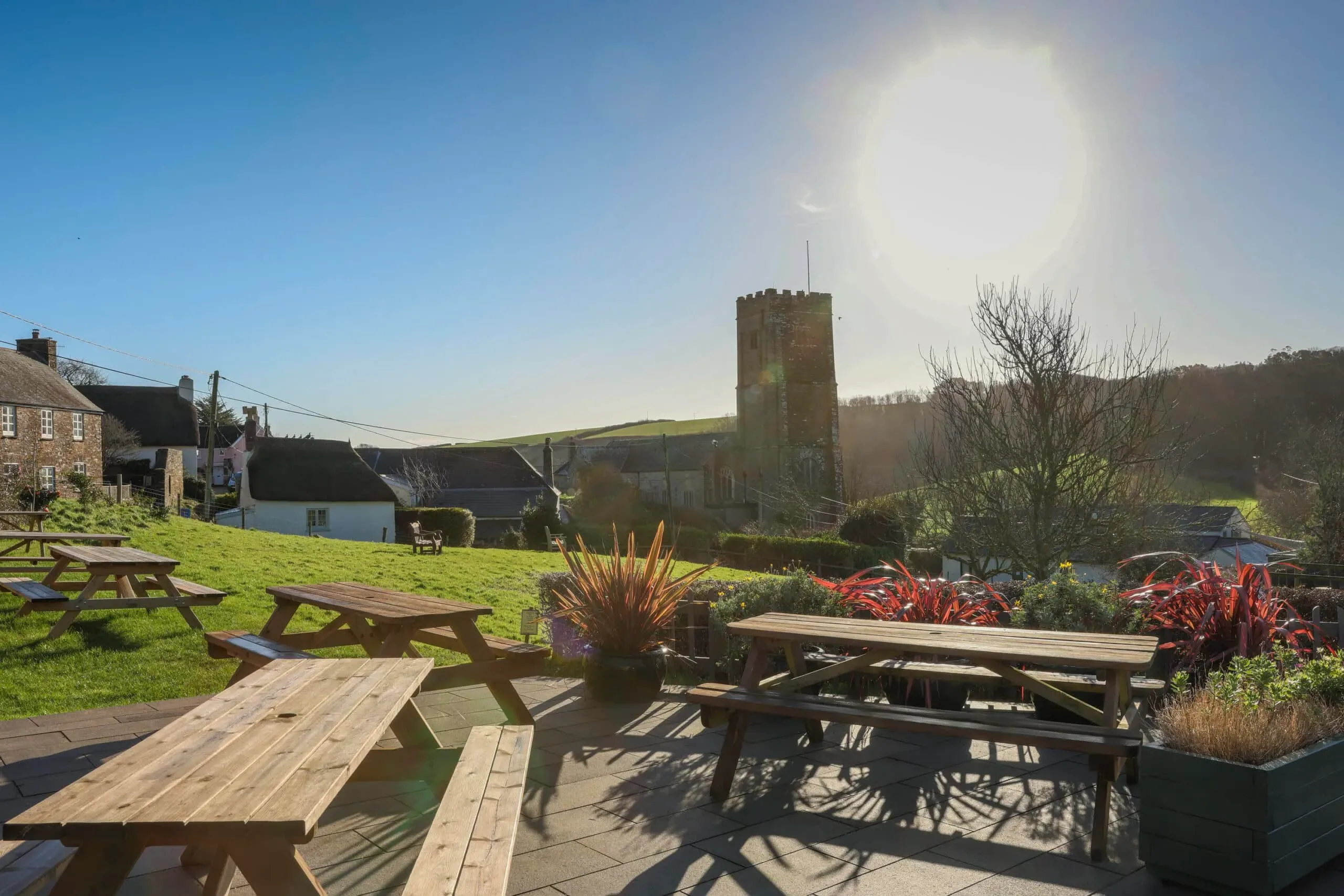 Village pub garden with picnic tables and the church tower beyond